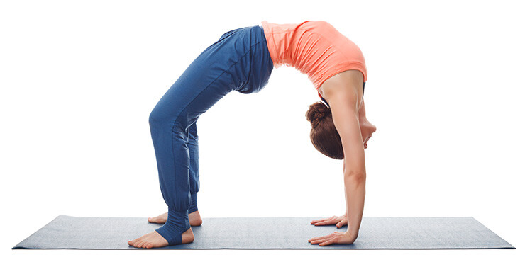 woman standing in the wheel yoga pose, also know as chakrasana