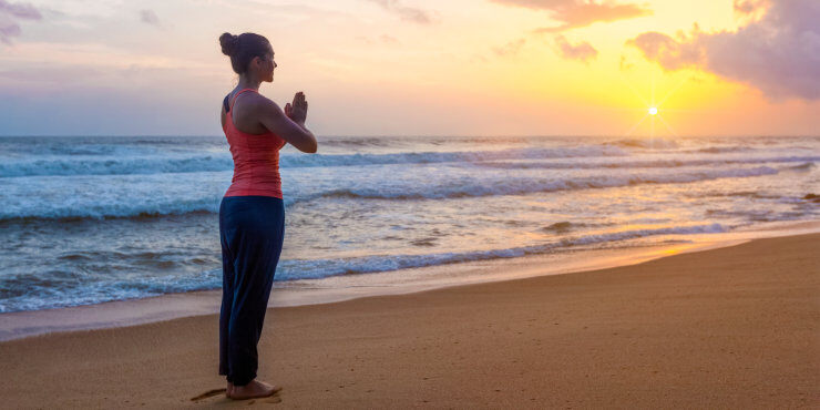 woman performing mountain pose (tadasana) on the beach